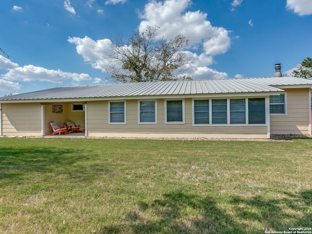 back of property with a lawn and a patio