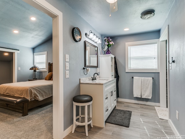 bathroom with a wealth of natural light, lofted ceiling, hardwood / wood-style flooring, and vanity