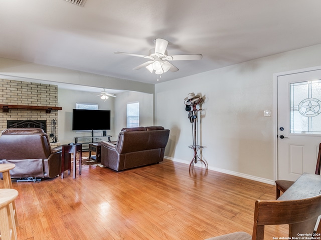 living room with wood-type flooring, ceiling fan, and a brick fireplace