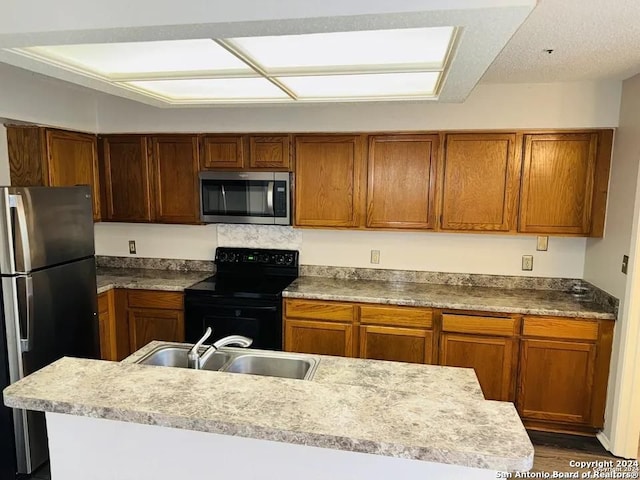 kitchen with stainless steel appliances, dark wood-type flooring, a kitchen island with sink, and sink