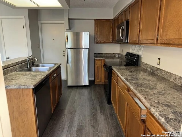 kitchen with sink, appliances with stainless steel finishes, dark hardwood / wood-style flooring, and a textured ceiling