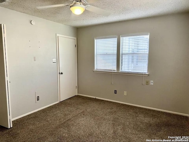 unfurnished room with dark carpet, a textured ceiling, and ceiling fan