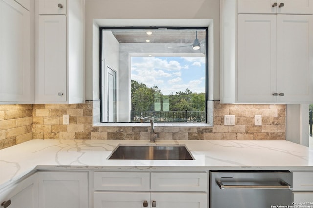 kitchen with light stone counters, sink, backsplash, white cabinetry, and dishwasher