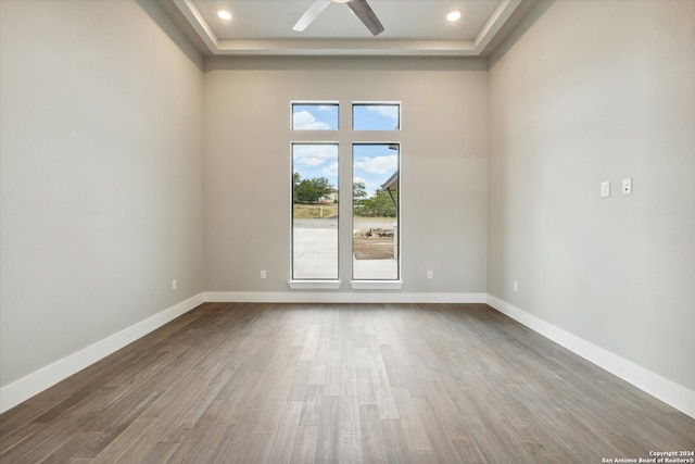 unfurnished room featuring a towering ceiling, a tray ceiling, hardwood / wood-style floors, and ceiling fan