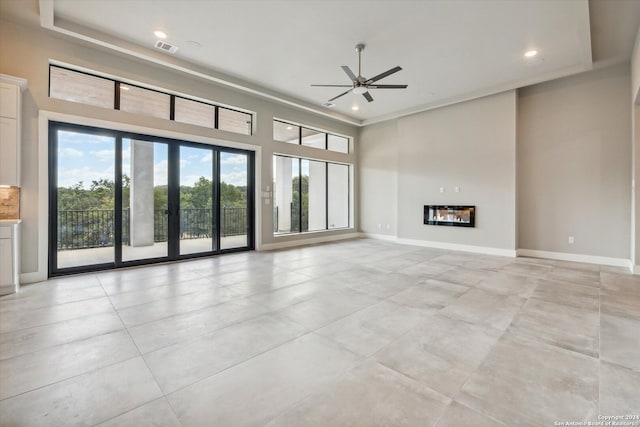 unfurnished living room with ceiling fan, light tile patterned floors, and a high ceiling