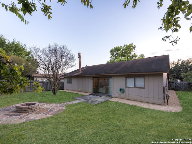 back of house featuring a lawn, a patio, and an outdoor fire pit