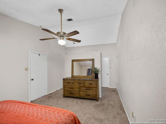 bedroom featuring light carpet, a textured ceiling, and ceiling fan