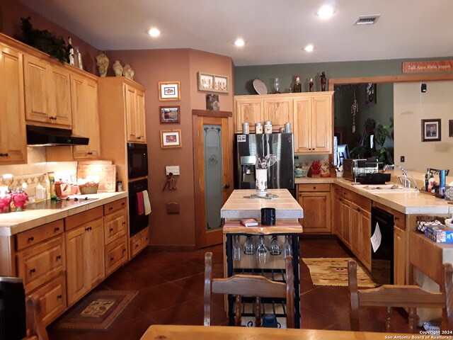 kitchen with dark tile patterned floors, sink, decorative backsplash, black appliances, and light brown cabinets