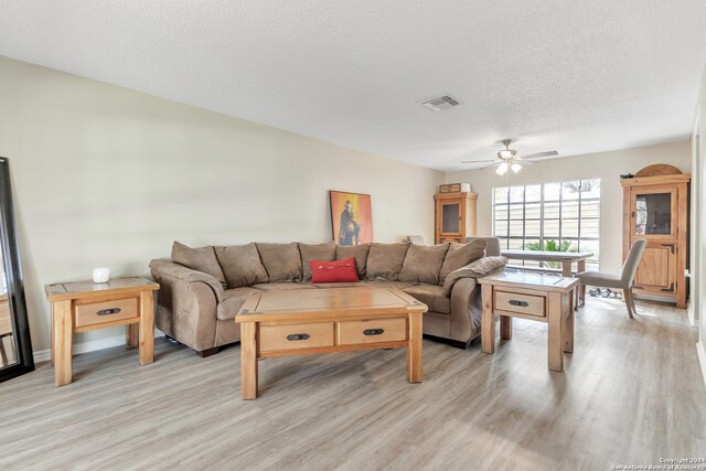 living room with light hardwood / wood-style flooring, ceiling fan, and a textured ceiling