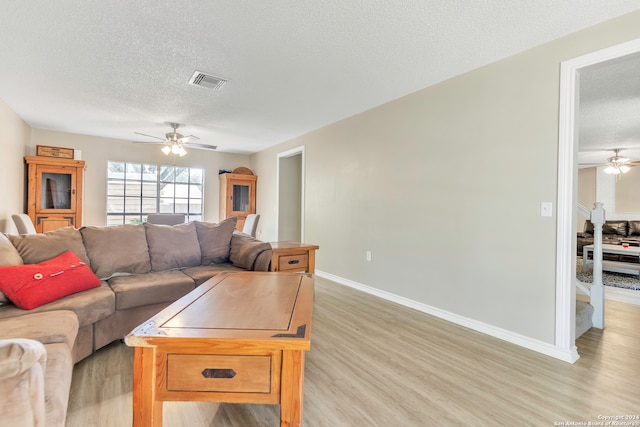 living room featuring a textured ceiling, light hardwood / wood-style floors, and ceiling fan