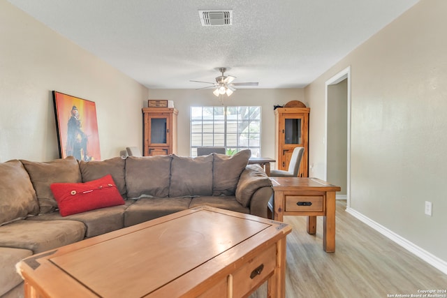 living room featuring ceiling fan, a textured ceiling, and light wood-type flooring