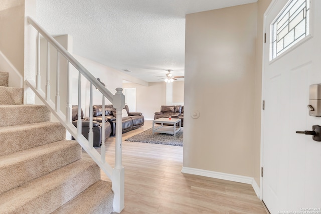 staircase with ceiling fan, a textured ceiling, and hardwood / wood-style floors