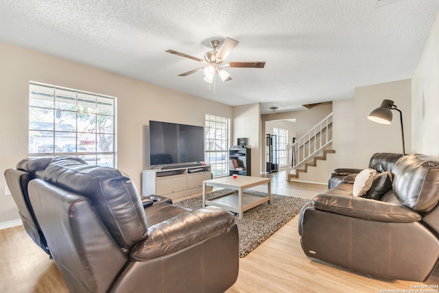 living room with ceiling fan, a textured ceiling, and light hardwood / wood-style floors