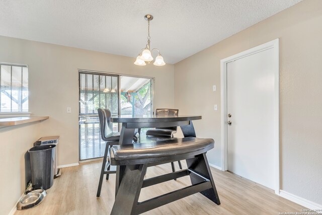 dining area featuring a textured ceiling, a chandelier, and light hardwood / wood-style floors