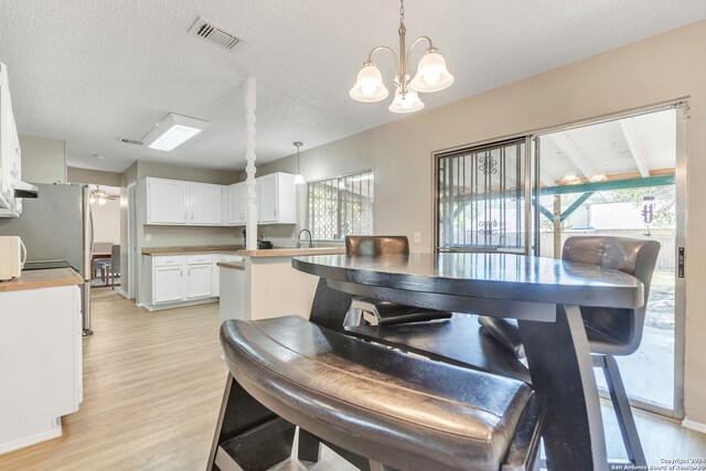 dining room with a textured ceiling, light wood-type flooring, and a healthy amount of sunlight