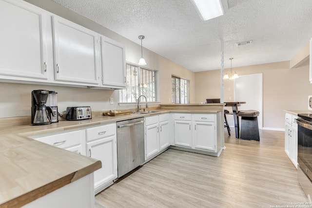 kitchen featuring appliances with stainless steel finishes, white cabinetry, and decorative light fixtures