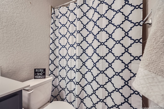 bathroom with walk in shower, vanity, and toilet