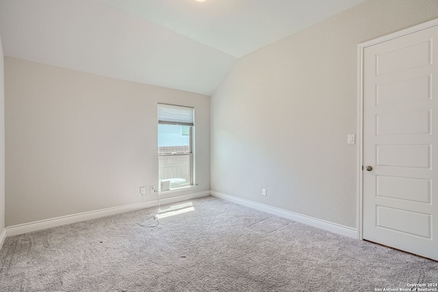 carpeted empty room with vaulted ceiling