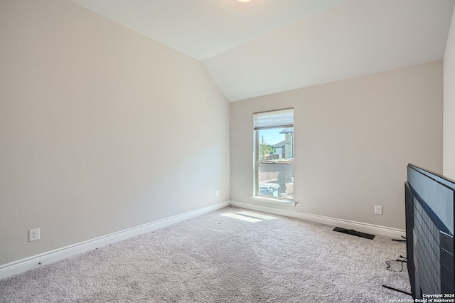 carpeted spare room with lofted ceiling