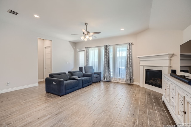 living room featuring light hardwood / wood-style floors, vaulted ceiling, and ceiling fan