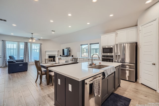 kitchen featuring light hardwood / wood-style floors, an island with sink, white cabinets, stainless steel appliances, and ceiling fan