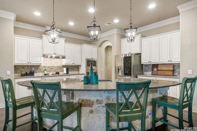 kitchen with stainless steel appliances, white cabinets, a kitchen bar, and a large island with sink