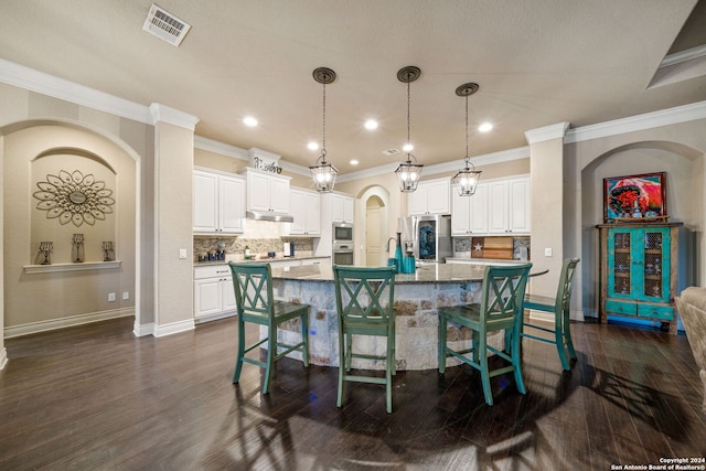 kitchen featuring a kitchen breakfast bar, a kitchen island with sink, dark wood-type flooring, and white cabinetry