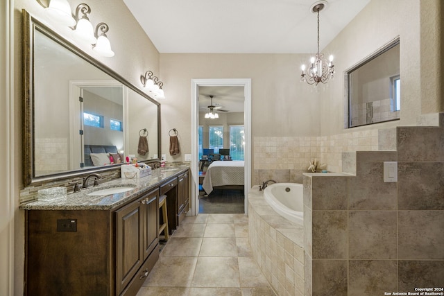 bathroom with a relaxing tiled tub, vanity, ceiling fan with notable chandelier, and tile patterned floors