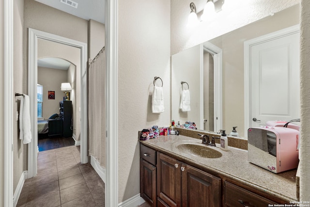 bathroom with walk in shower, tile patterned flooring, and vanity