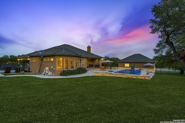 back house at dusk featuring a fenced in pool, a yard, and a patio