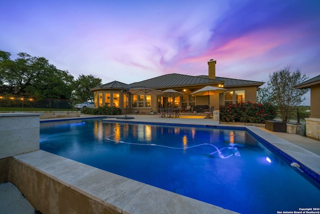 pool at dusk featuring a patio