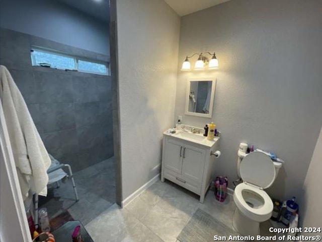 bathroom with a tile shower, vanity, and toilet