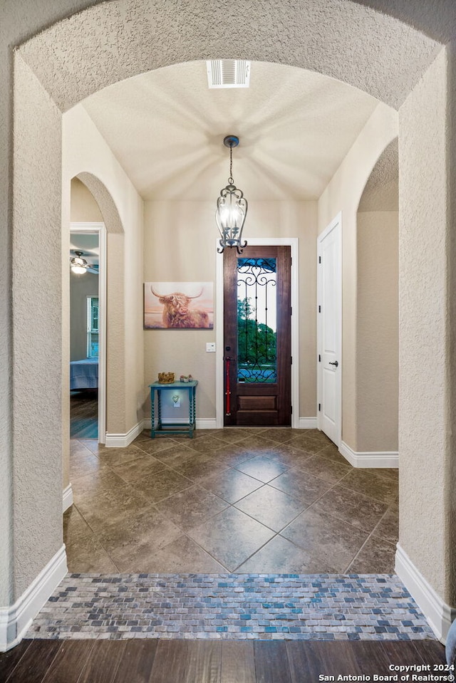 foyer with a textured ceiling and ceiling fan with notable chandelier