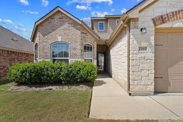 doorway to property with a garage and a yard