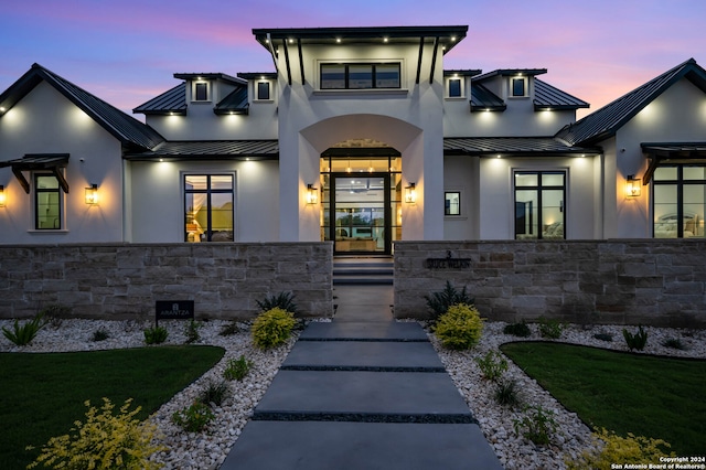 exterior entry at dusk featuring a lawn