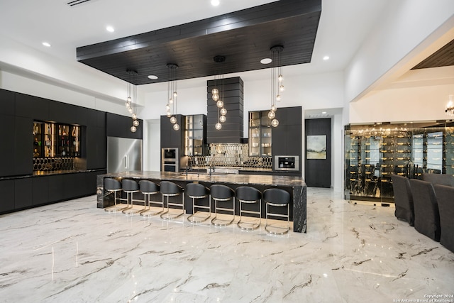 kitchen featuring backsplash, stainless steel appliances, decorative light fixtures, dark stone counters, and a large island