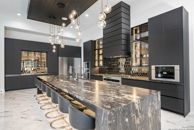 kitchen featuring pendant lighting, stainless steel appliances, backsplash, and a spacious island