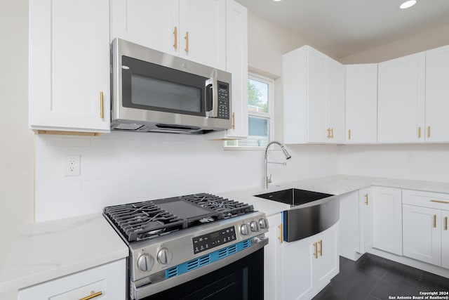 kitchen featuring light stone counters, white cabinets, stainless steel appliances, and sink