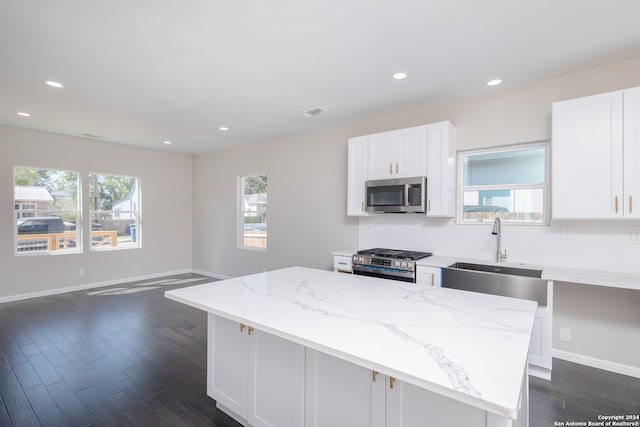 kitchen with white cabinets, stainless steel appliances, sink, and a kitchen island