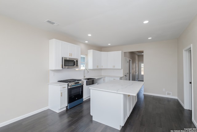 kitchen featuring stainless steel appliances, white cabinets, dark hardwood / wood-style flooring, and a center island