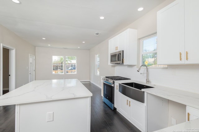 kitchen featuring light stone counters, white cabinets, stainless steel appliances, dark hardwood / wood-style floors, and a center island