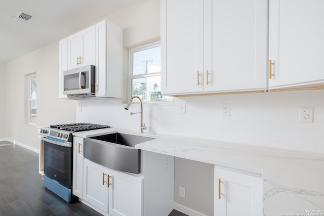 kitchen featuring stainless steel appliances, white cabinets, and light stone counters