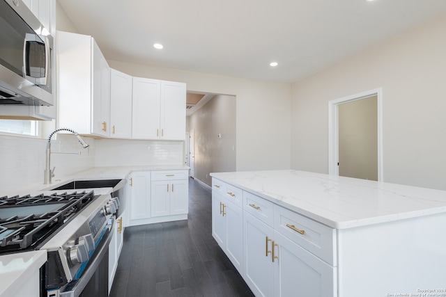 kitchen featuring dark wood-type flooring, light stone counters, backsplash, appliances with stainless steel finishes, and white cabinetry