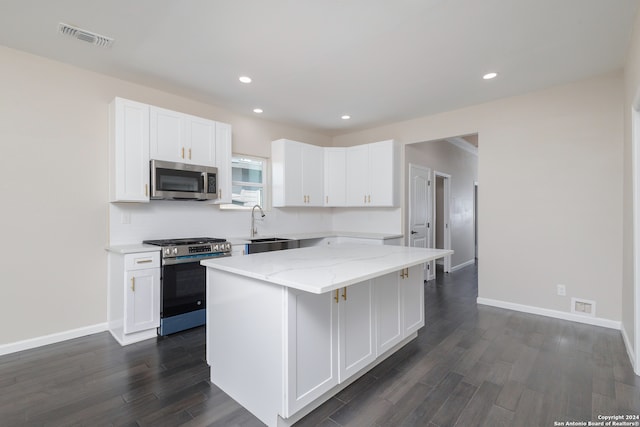 kitchen featuring appliances with stainless steel finishes, dark wood-type flooring, white cabinetry, and a center island