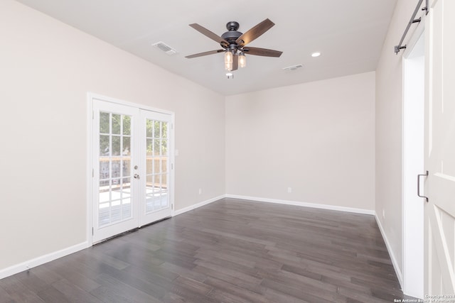 spare room with dark wood-type flooring, french doors, a barn door, and ceiling fan