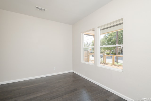 empty room featuring a healthy amount of sunlight and dark hardwood / wood-style flooring