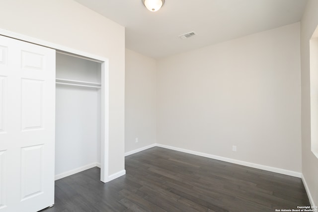 unfurnished bedroom featuring a closet and dark hardwood / wood-style flooring