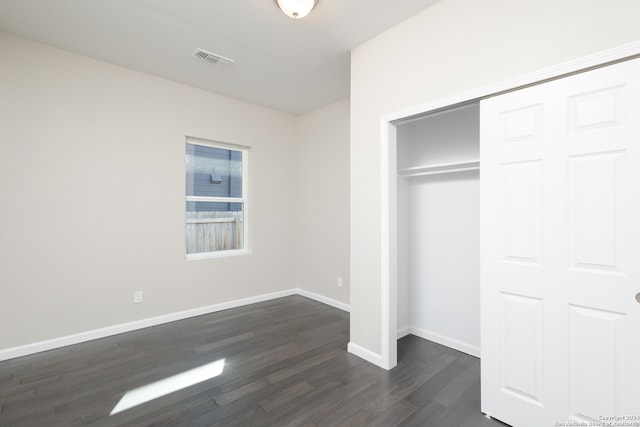 unfurnished bedroom with a closet and dark hardwood / wood-style floors