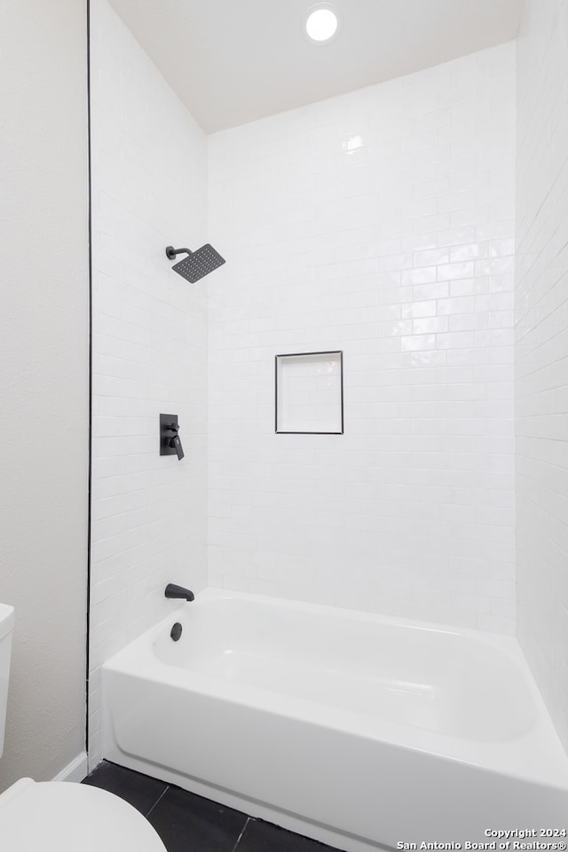 bathroom with tile patterned flooring, tiled shower / bath combo, and toilet