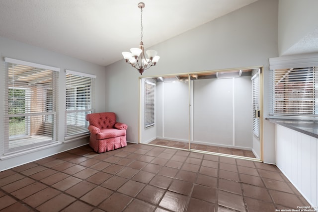 interior space with a notable chandelier, dark tile patterned flooring, and vaulted ceiling